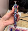 Foto eines Diamant-Stifts im Sternenhimmel-Stil mit glänzenden lila und blauen Pailletten, ideal für deine Diamond Painting-Projekte.