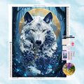 5D Diamond Painting Motiv: Ein majestätischer weißer Wolf mit tiefblauen floralen Mustern auf dem Fell, der vor einem leuchtend goldenen Mond im dunklen Wald steht.