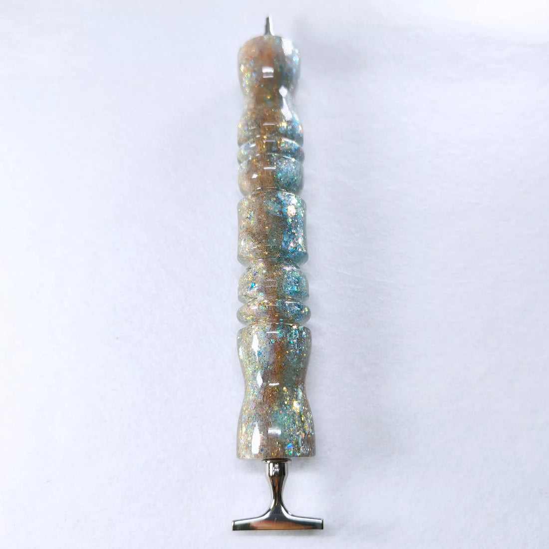 Ergonomischer Stift aus Kunstharz mit glänzendem Finish im Farbverlauf von Goldsand zu Lagunenblau mit Glitzerpartikeln.
